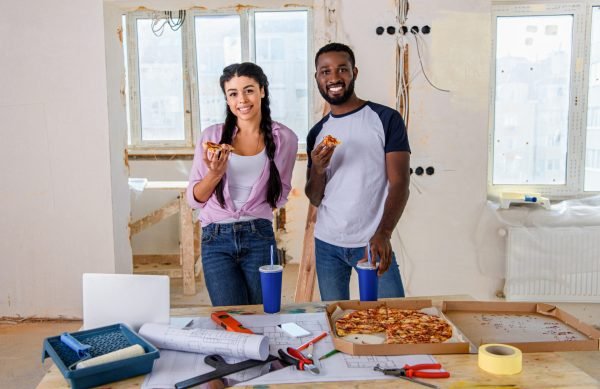 smiling young couple eating pizza while making renovation of home smiling young couple eating pizza while making renovation of home